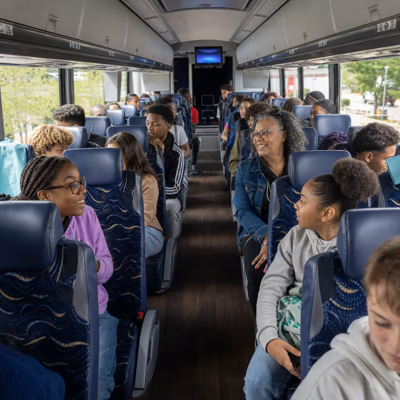 Group boarding a white charter bus for School Transportation transportation in Bellevue